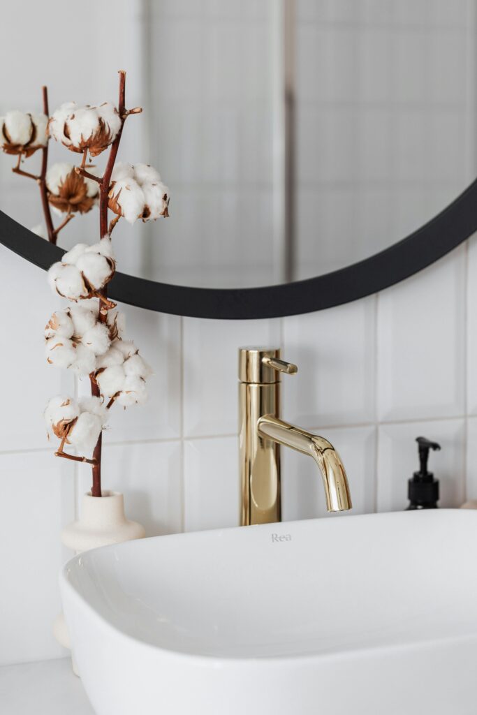 Stylish bathroom featuring a sleek golden faucet and cotton plant decoration.